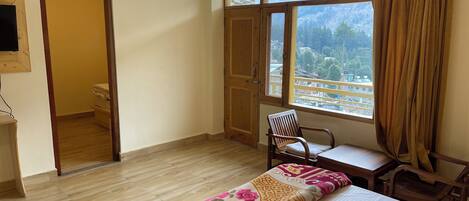 A hotel room with a bed, a desk, a chair, and a large window with curtains.
