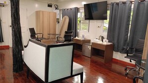 Una habitación con una cama, un escritorio, una silla, un televisor y una ventana con cortinas.