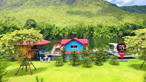 Un resort con un edificio azul y techos rojos, rodeado de exuberante vegetación y un lago.