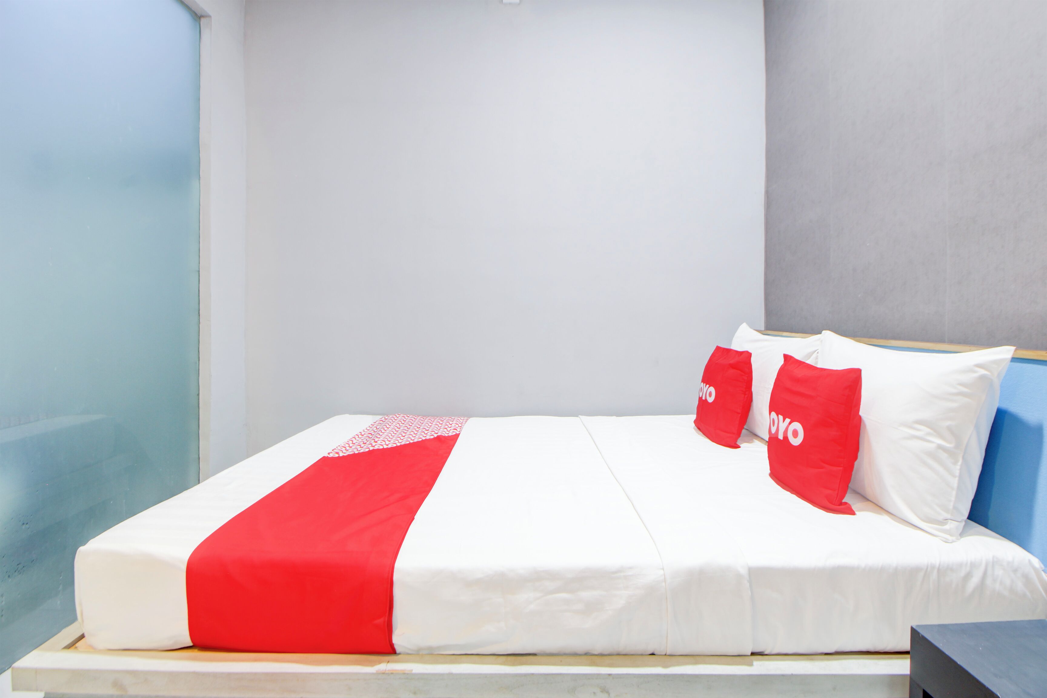 A bed with white and red bedding, two red pillows with "YOYO" text, and a wooden headboard.