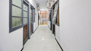 Un couloir doté d’un sol carrelé brillant, de grandes fenêtres équipées de stores et de climatiseurs fixés aux murs.