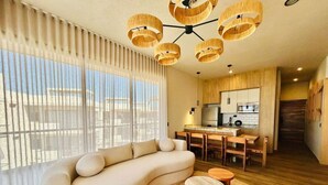 Un salon moderne avec un canapé aux lignes courbes, un coin repas et une cuisine.