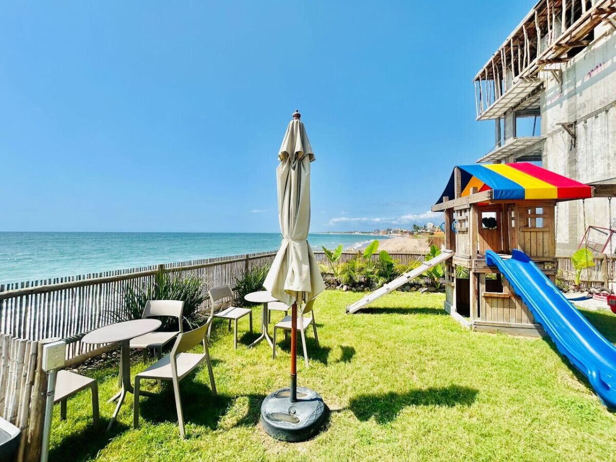 A patio with outdoor seating and a slide, overlooking a beach.