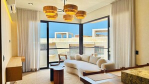 Un salon moderne avec un canapé, une table basse et une grande fenêtre donnant sur des immeubles.