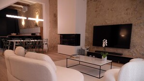 A modern living room with a sofa, a coffee table, and a flat-screen TV mounted on a textured wall.