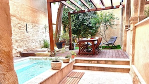 A wooden deck with a pool, outdoor furniture, and potted plants.