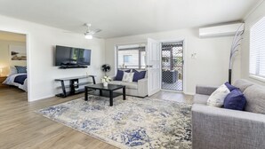 Een moderne woonkamer met een flatscreen televisie, een salontafel, een bank en een kamerbreed tapijt met een patroon.