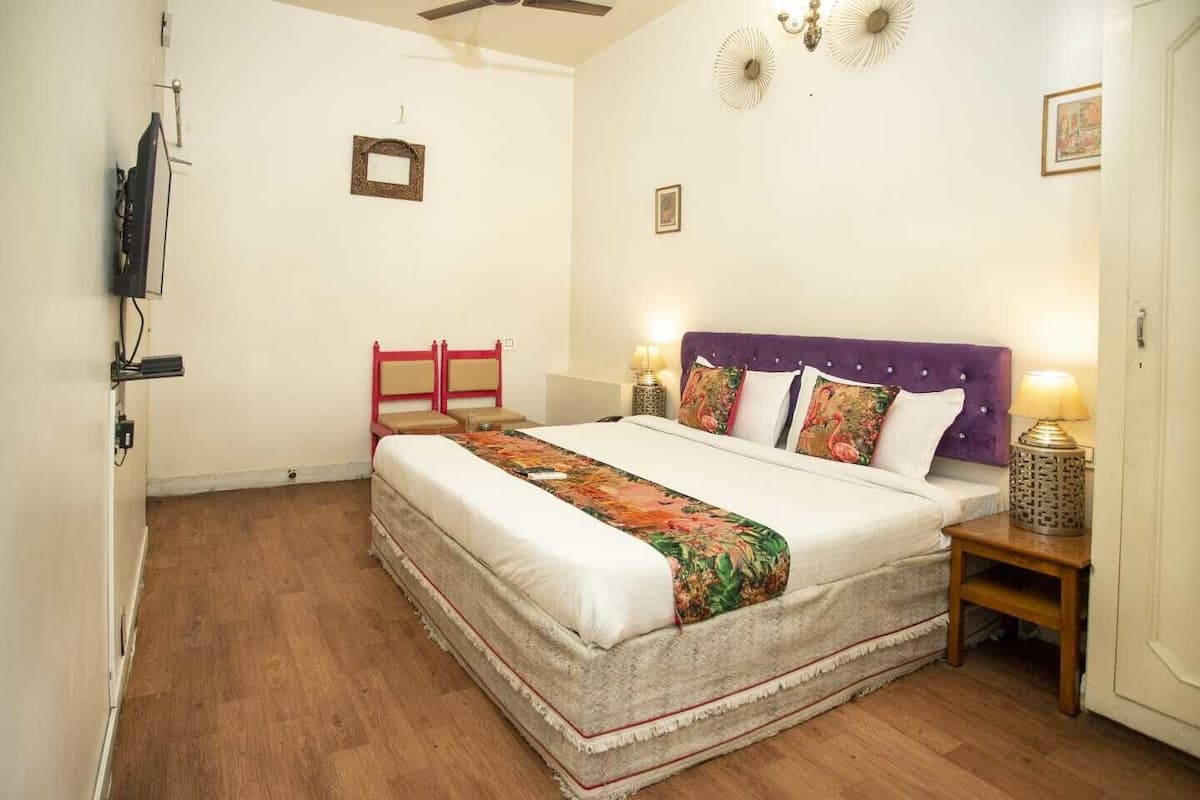 A bedroom with a bed, a nightstand, a chair, and a ceiling fan.