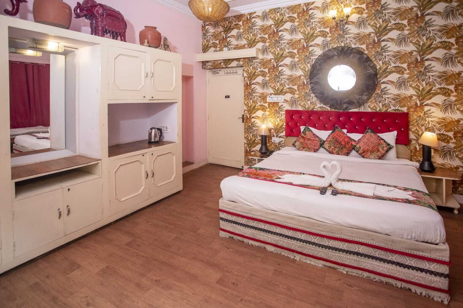 Ein Schlafzimmer mit einem Bett, einem Kleiderschrank, einem Spiegel und einer Wand mit tropischem Blattmuster.