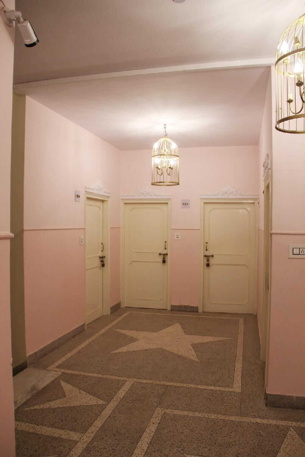 Un pasillo con tres puertas, un suelo estampado con motivos de estrellas y una lámpara colgante.