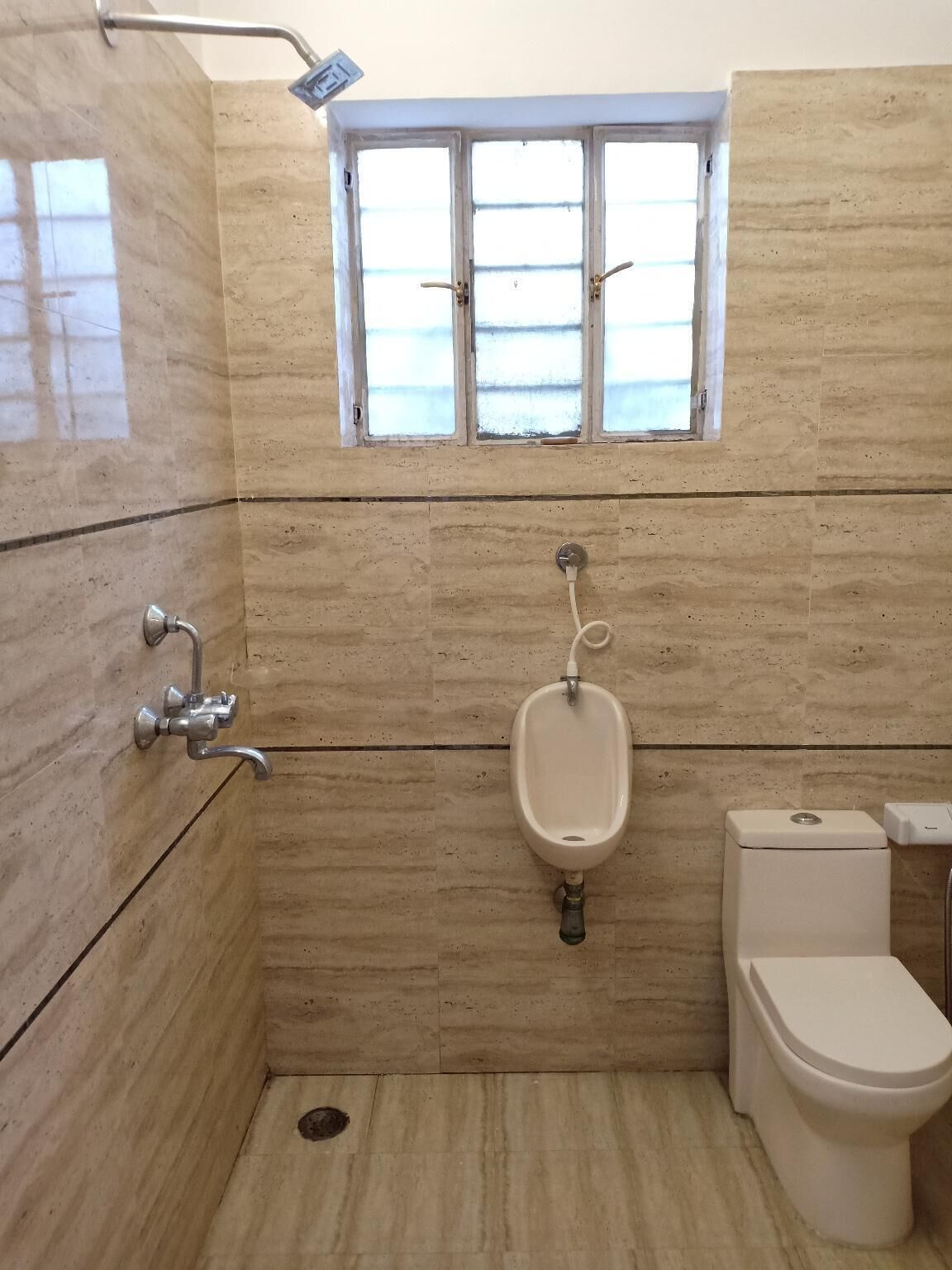 Une salle de bain équipée d’une douche, d’un urinoir et de toilettes.
