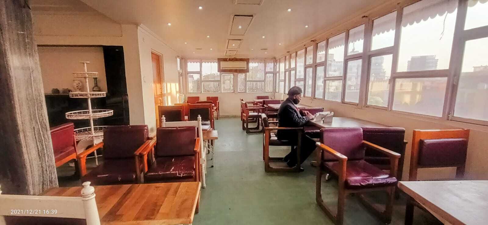 Un restaurante espacioso con techos altos, ventanas amplias y una combinación de asientos de madera y acolchados.