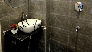 Ein Badezimmer mit einem weißen Waschbecken, einem runden Spiegel und einer Duschkabine.