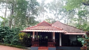 A small, single-story building with a tiled roof and a porch area. - Humble Nest Coorg (Somvarpet)
