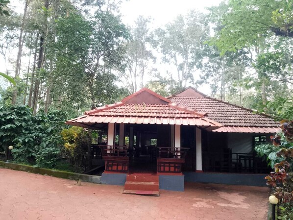 A small, single-story building with a tiled roof and a porch area. - Humble Nest Coorg (Somvarpet)