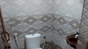 A small bathroom with a toilet, a shower, and a sink. - Humble Nest Coorg (Somvarpet)