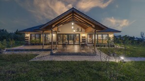 Een modern huis met een overdekte patio, grote ramen en een goed verlichte entree.