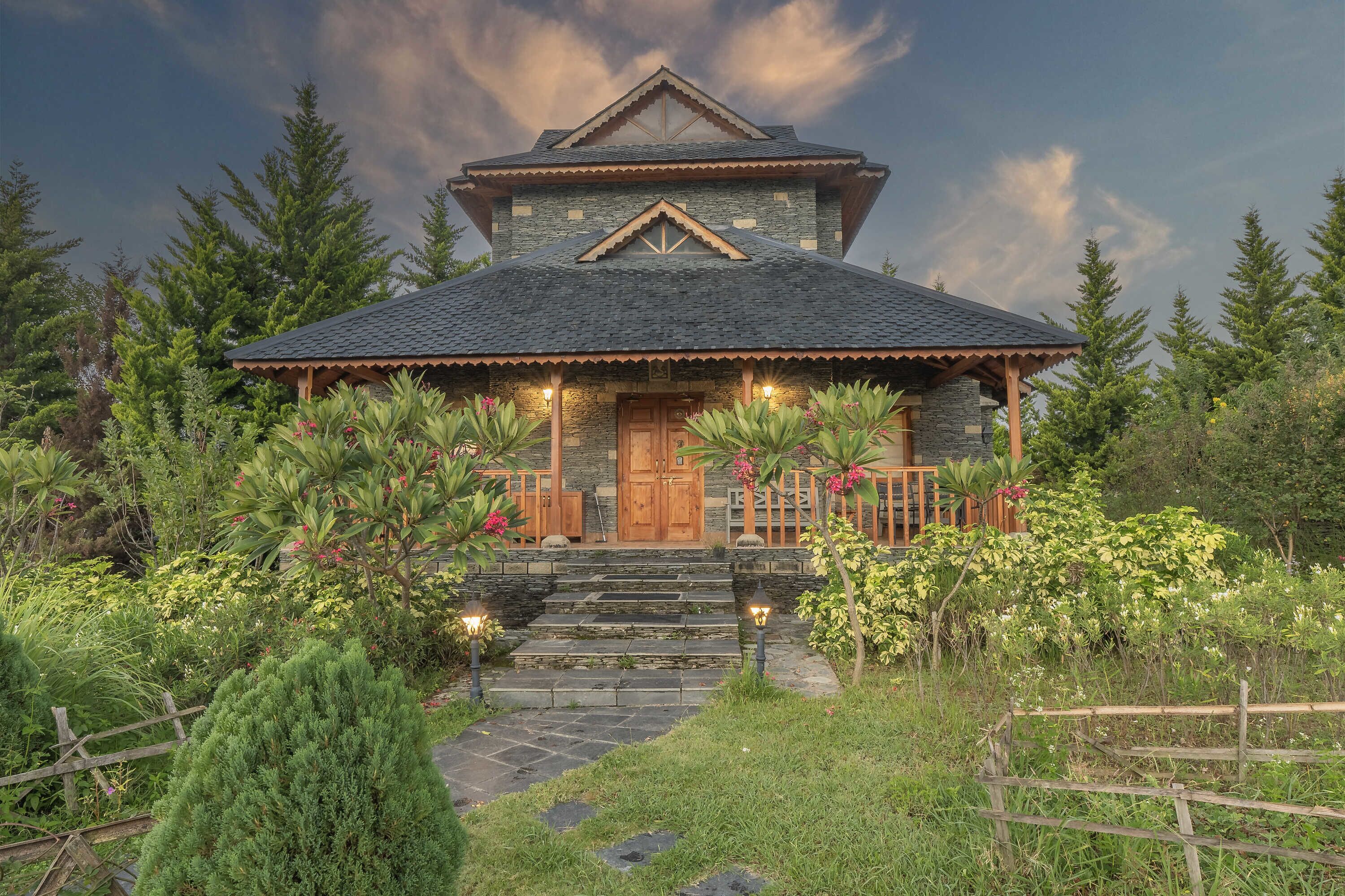 A two-story house with a stone facade, a wooden front porch, and a steeply pitched roof.