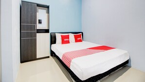 A bedroom with a bed, a wardrobe, and a wall-mounted air conditioner. - Hotel O Alun-Alun Purwokerto Near Gor Satria Purwokerto Formerly Guest House Blessing (Purwokerto)