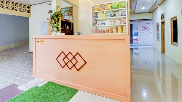 A reception area with a wooden counter, a plant, and a shelf with snacks. - Hotel O Alun-Alun Purwokerto Near Gor Satria Purwokerto Formerly Guest House Blessing (Purwokerto)