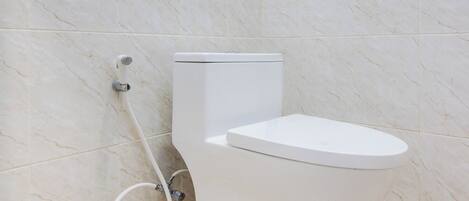 A bathroom with a toilet, a shower, and a tiled floor.