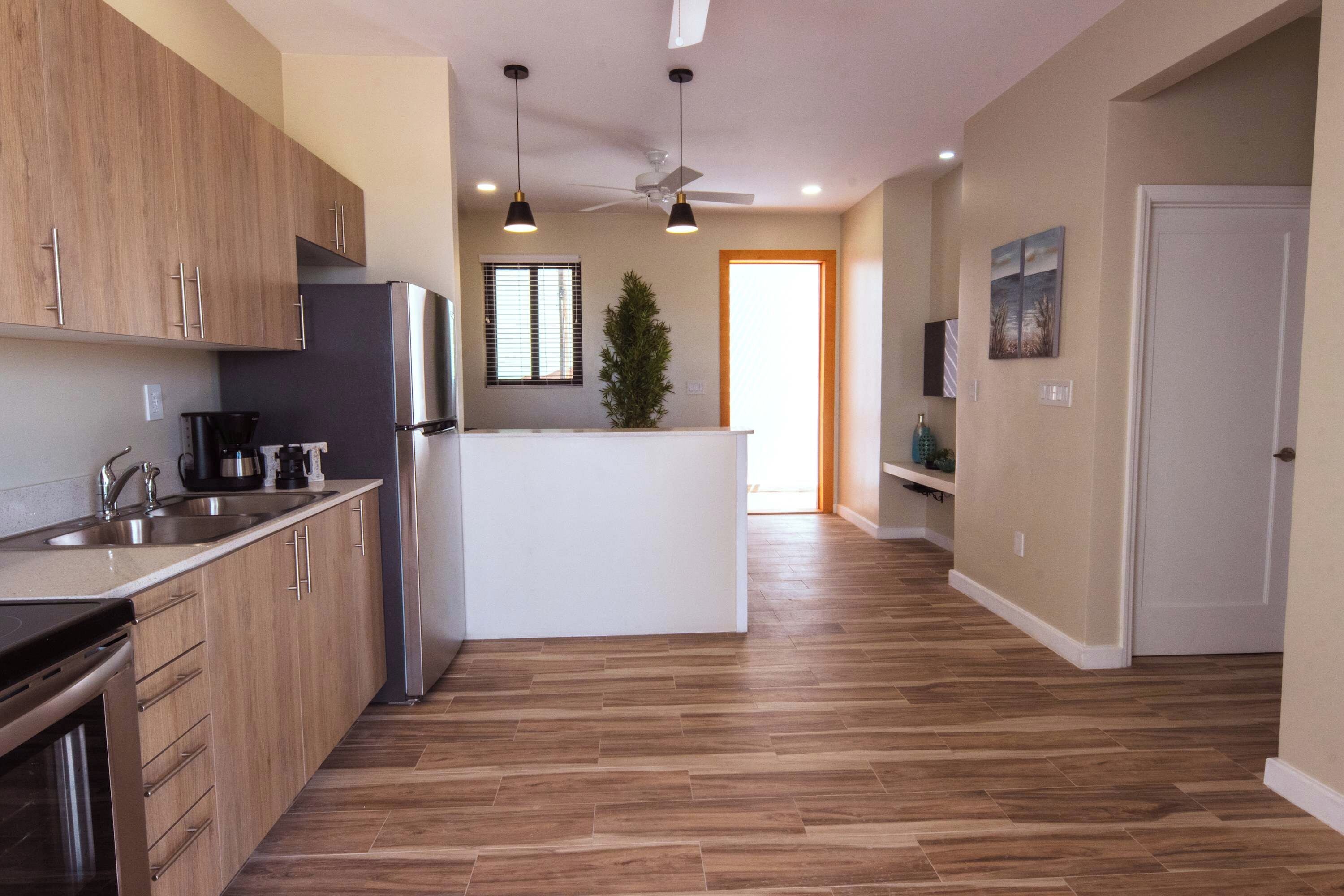 Een moderne keuken met houten kastjes, een roestvrijstalen koelkast en een centraal eiland.