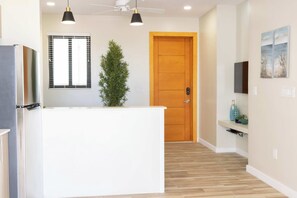 A modern kitchen with a white island, black pendant lights, a wooden door, and a small plant. - Tropical Apartment Near Long Bay with Pool Access (Leeward Settlement)
