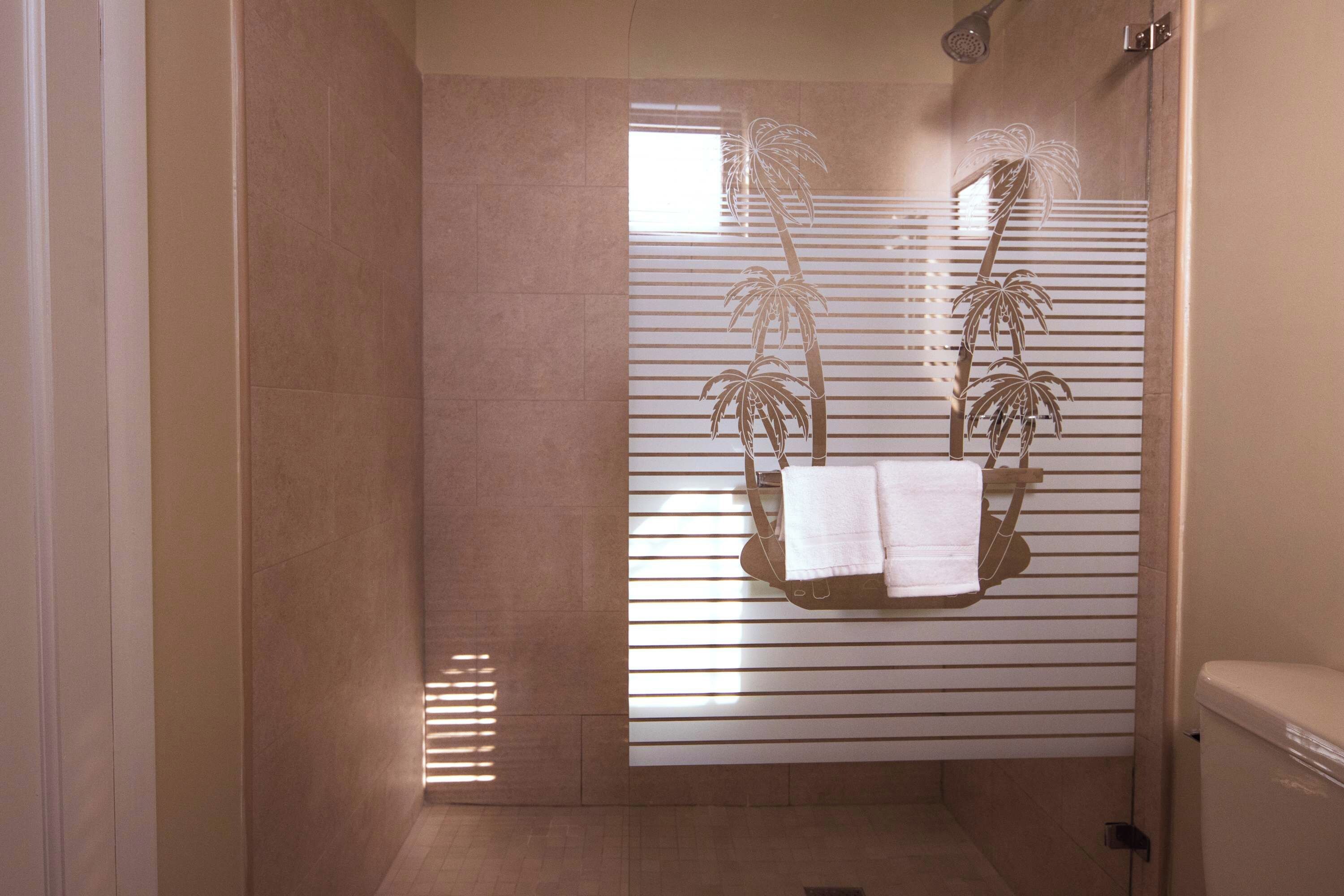 Un baño con ducha, un perchero con toallas y una ventana con persianas.