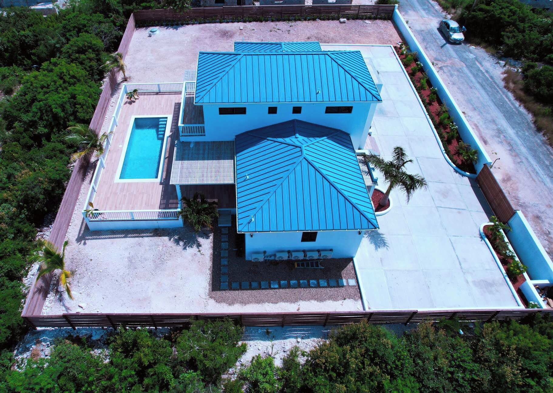 A two-story building with a blue roof, a swimming pool, and a paved driveway.