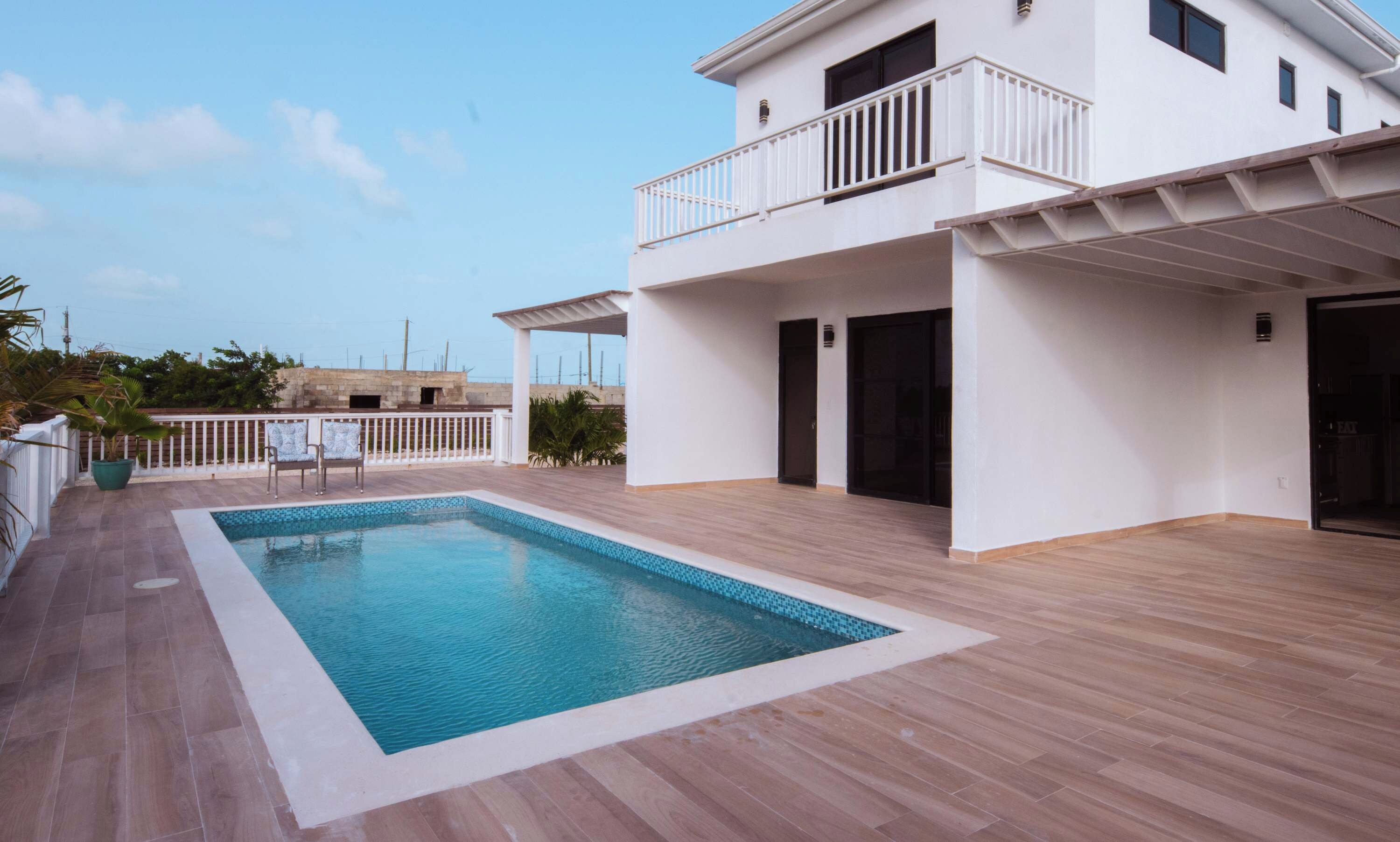 Un bâtiment moderne à deux étages, doté d’une piscine, d’un patio couvert et offrant une vue sur les environs.