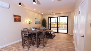 A dining area with a wooden table and chairs, a ceiling fan, and a view through a glass door to an outdoor balcony. - Private Pool Villa Near Long Bay Beach & Grace Bay (Leeward Settlement)