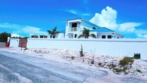 A modern two-story house with a blue roof, white walls, and a balcony. - Private Pool Villa Near Long Bay Beach & Grace Bay (Leeward Settlement)