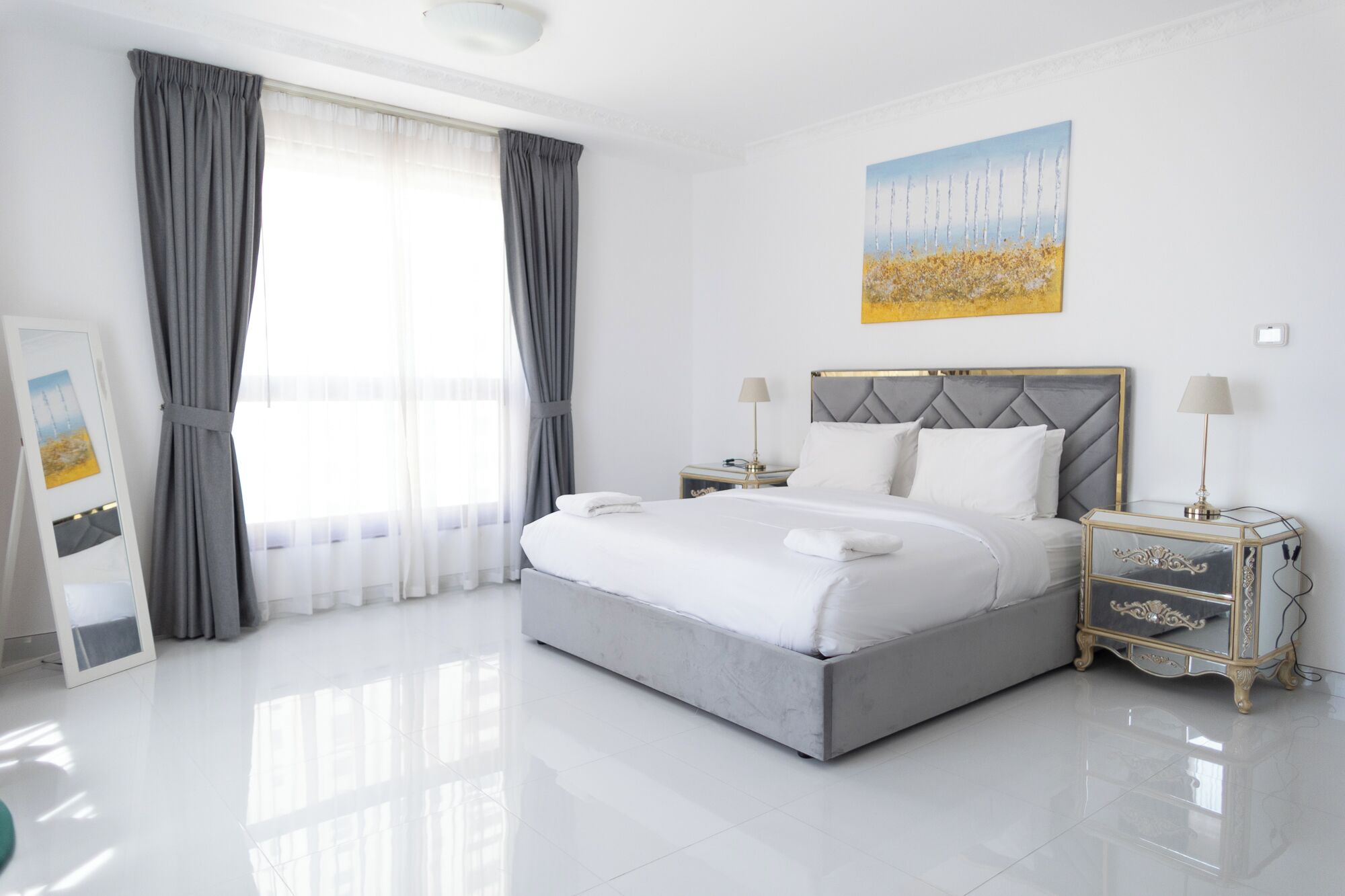 Een moderne hotelkamer met een groot bed, twee nachtkastjes en een schilderij aan de muur.