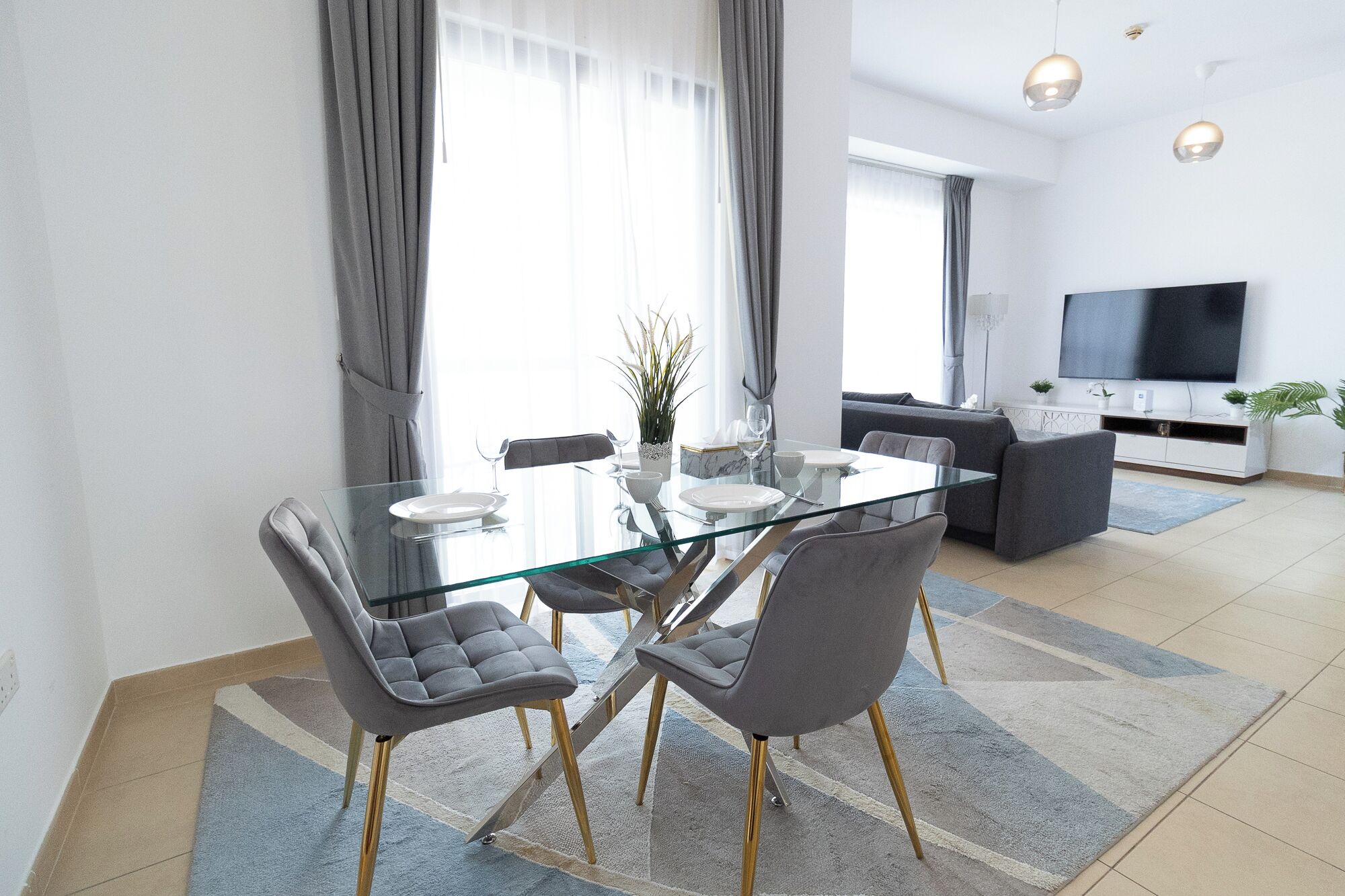 Un'area pranzo moderna con un tavolo in vetro, sedie rivestite in grigio e un arredamento minimalista.