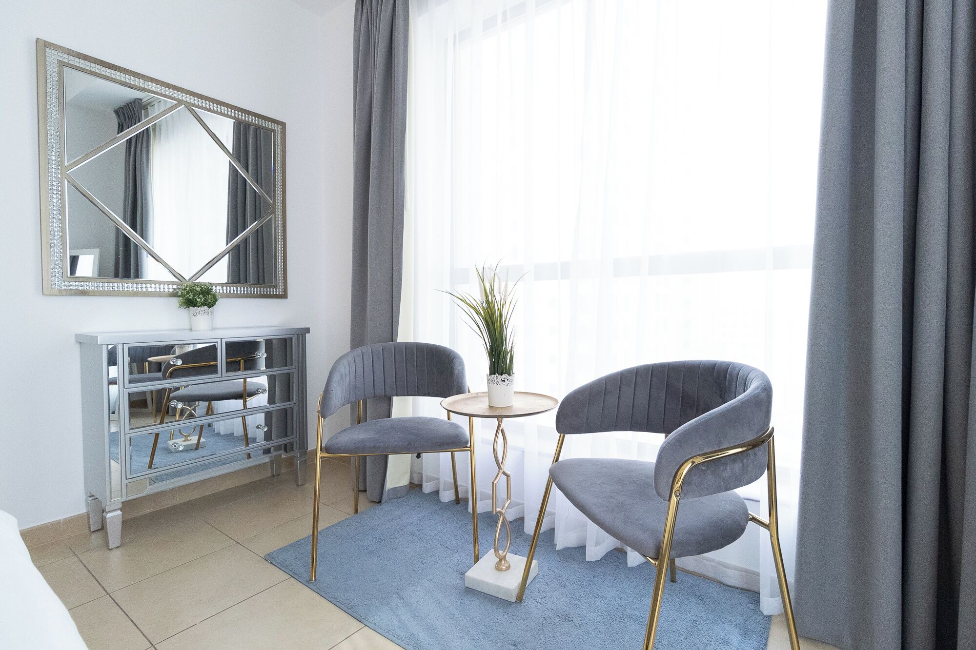 Una sala de estar moderna con un sofá gris, una mesita redonda y un mueble con espejo.