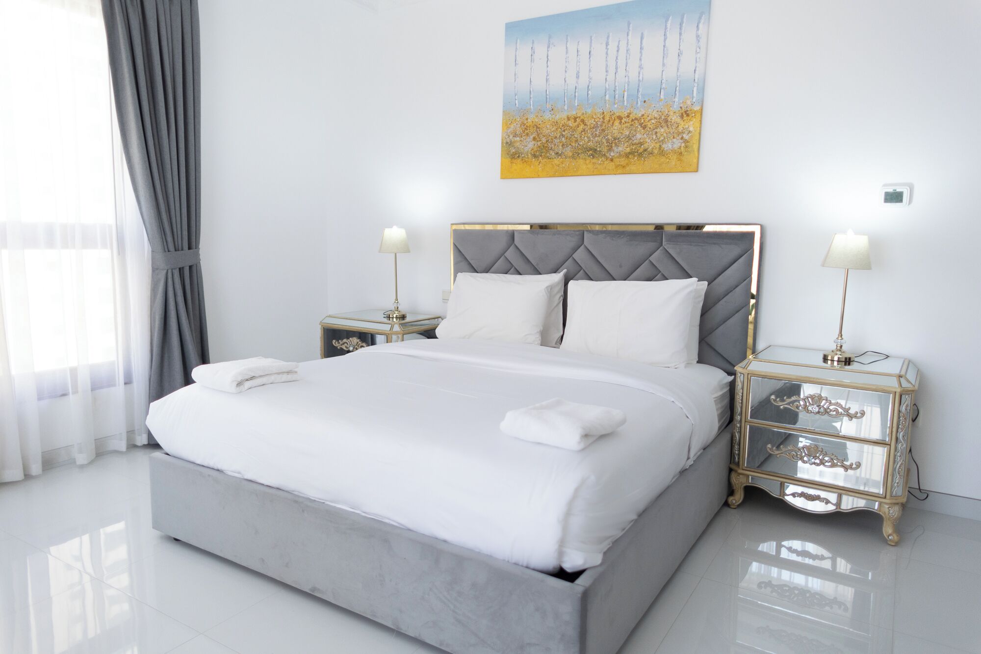 Une chambre moderne avec un grand lit, deux tables de chevet et un tableau accroché au mur.