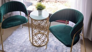 A room with a view of the ocean, two green chairs, a small table with a plant, and a white rug. - HAPPY SEASON | Apartment on JBR  (Dubai)