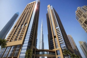 A high-rise building with a prominent central tower, surrounded by other tall structures. - HAPPY SEASON | ACT ONE ACT TWO (Dubai)