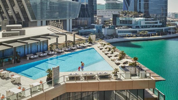 A rooftop pool with lounge chairs and a view of the cityscape. - HAPPY SEASON | Four Season apartment  (Abu Dhabi)
