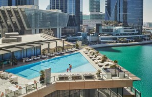 A rooftop pool with lounge chairs and a view of the cityscape. - HAPPY SEASON | Four Season apartment  (Abu Dhabi)