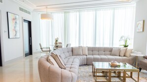 A spacious living room with a large L-shaped sectional sofa, a glass coffee table, and a dining area with a small table and chairs. - HAPPY SEASON | Four Season apartment  (Abu Dhabi)