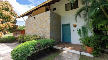 Set amidst lush greenery, this residence features a stone facade and a flat roof with a wooden overhang.