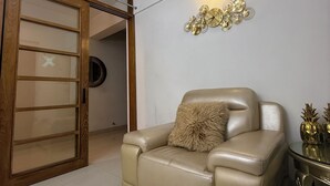 Ett rum med en beige lädersoffa, en skjutdörr i trä och en dekorativ väggklocka.