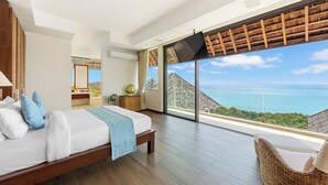 A spacious bedroom with a large bed, a television, and a view of the ocean.