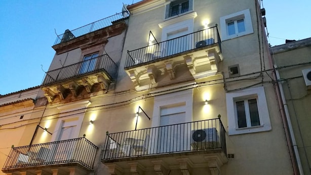 Een meerhoog gebouw met balkons, airconditioning en een reeks ramen.