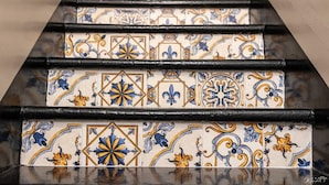 Een trap met decoratieve, patroonrijke tegels in blauw, geel en wit.