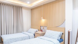 A hotel room with two beds, a nightstand, a wall-mounted heater, and a large window with curtains. - Charming 2-bedroom villa in gorgeous Tagaytay with AC, WiFi (Tagaytay)