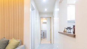 A hallway with a wooden panel wall, a sofa with cushions, and a shelf with decorative items. - Charming 2-bedroom villa in gorgeous Tagaytay with AC, WiFi (Tagaytay)