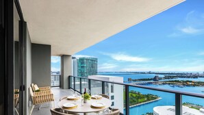 Ein Balkon mit einem runden Esstisch, der auf einen Hafen und die Skyline blickt.