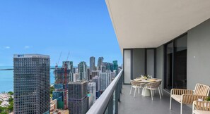 Un balcon avec vue sur la ville, une table avec des chaises et une bouteille de vin.